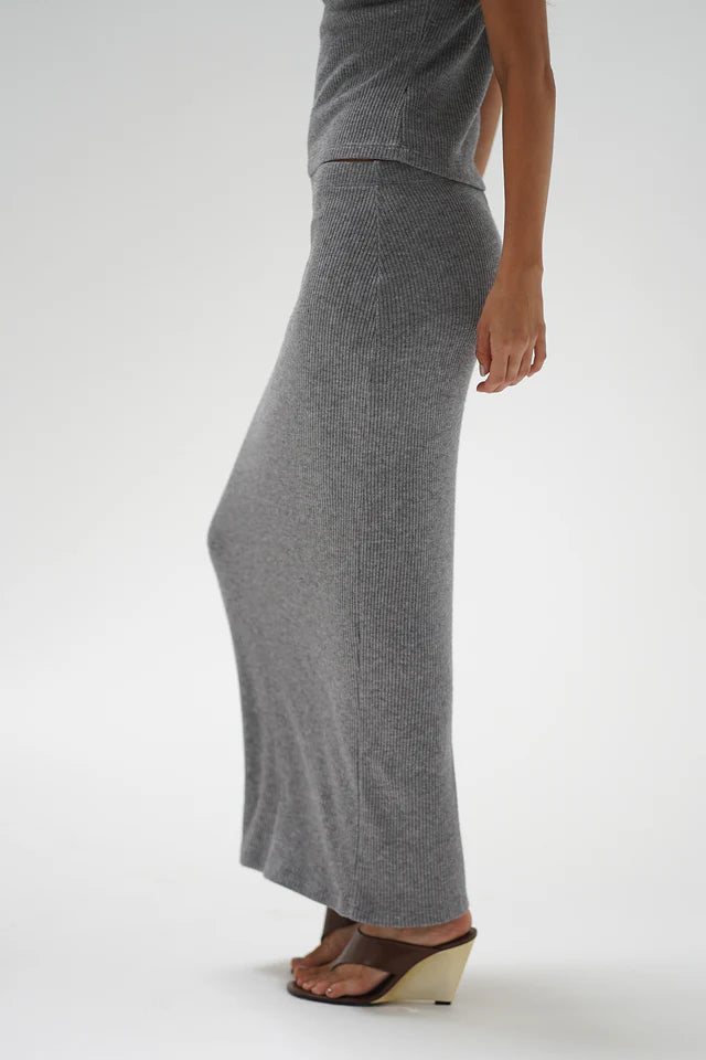 Person wearing a gray knit skirt on a white background