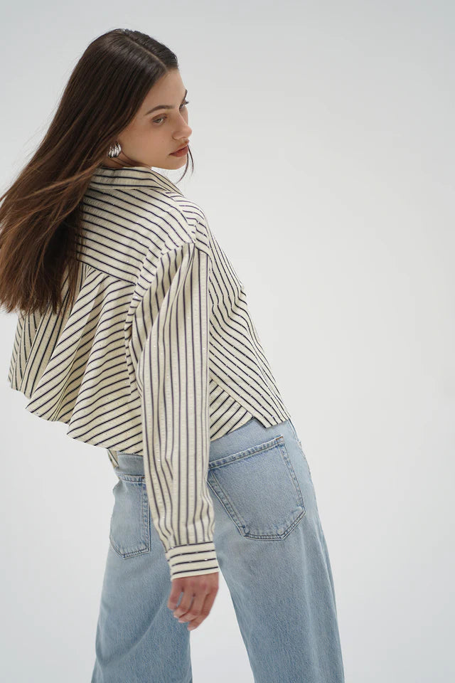 Woman wearing a striped shirt and light blue jeans on a white background