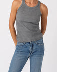 Person wearing a gray tank top and blue jeans on a white background