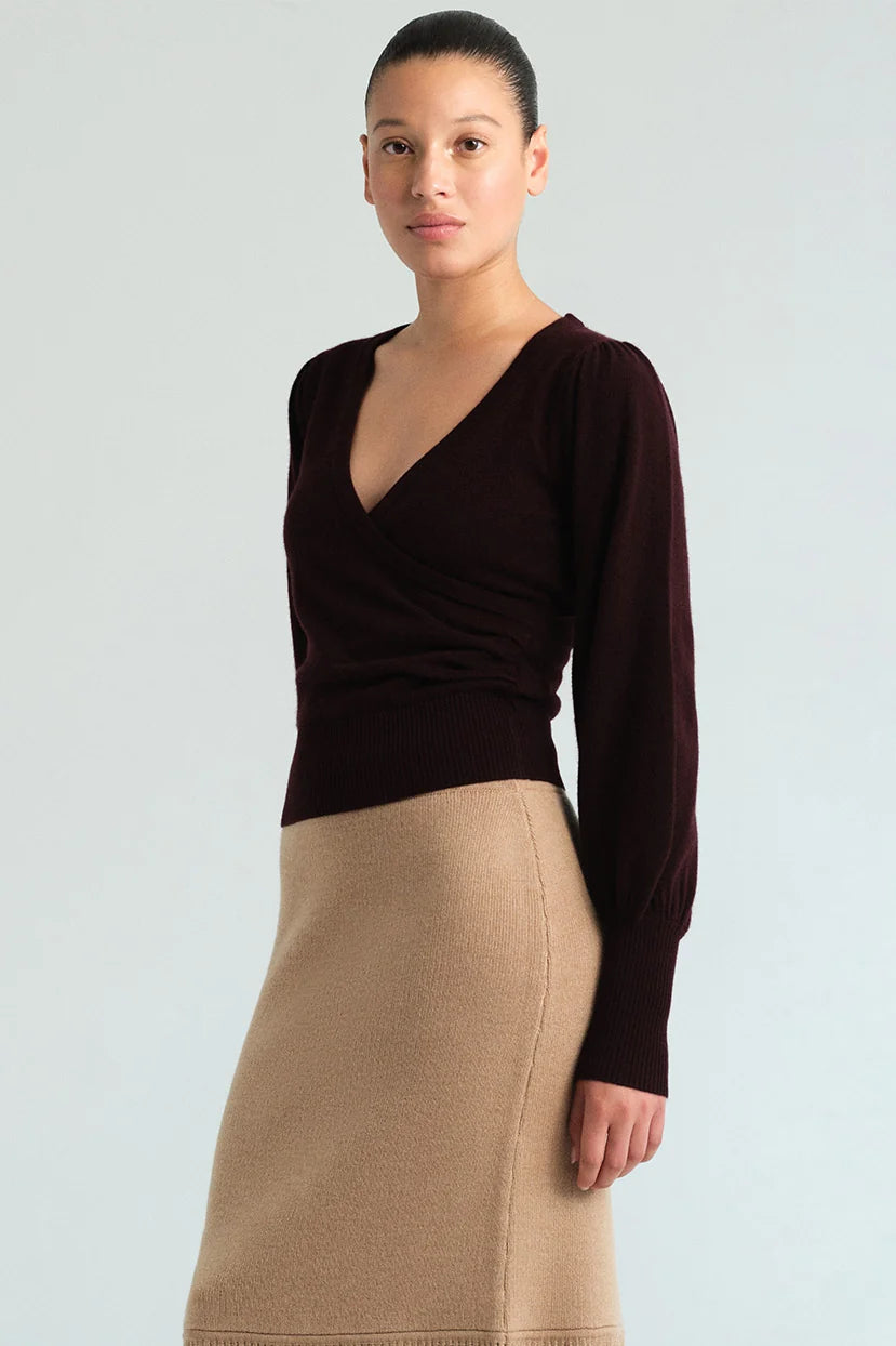 A model wearing a dark brown long-sleeve wrap-style top and a beige knit pencil skirt, photographed against a light gray studio background.