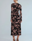 A woman viewed from the back wearing a long-sleeve midi dress with a black base and a dusty rose floral pattern, paired with black high-heeled sandals against a light gray studio background.
