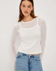 Woman wearing a white long-sleeve top and blue jeans on a plain background front view