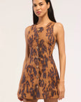 A woman modeling a sleeveless brown mini dress with a dark brown leopard print and a front button closure, set against a plain light background.