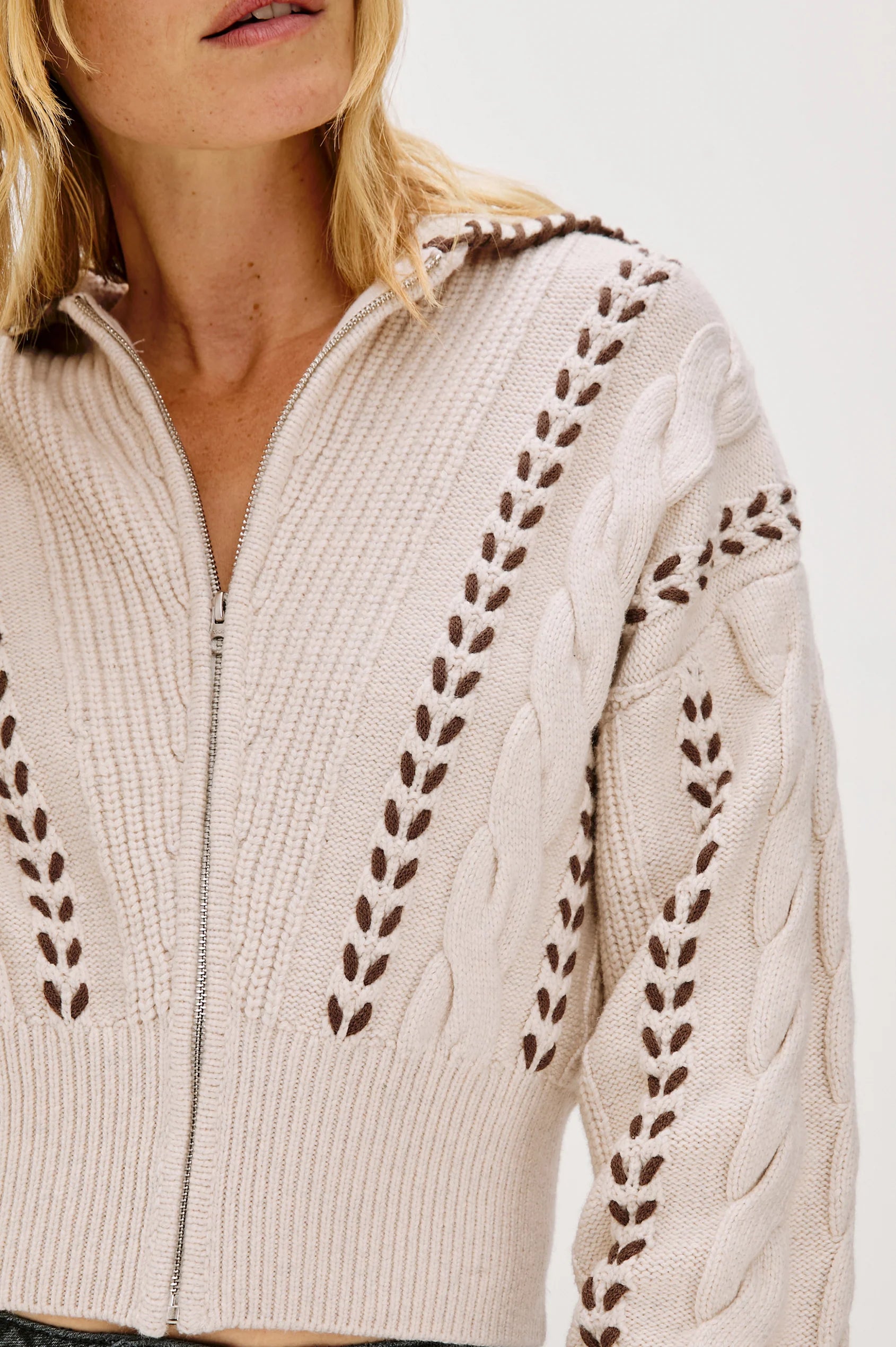 Beige sweater with intricate cable knit pattern on a white background