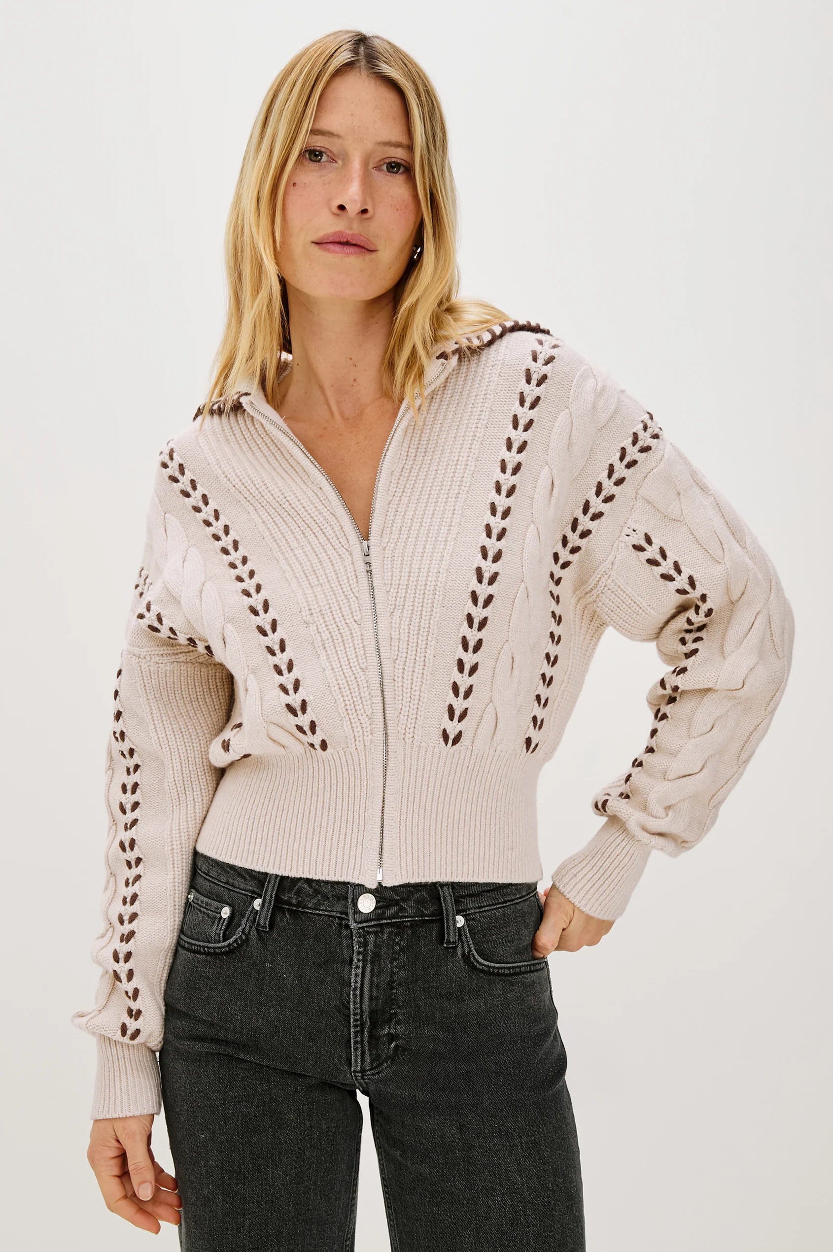 Woman wearing a beige zip-up sweater with details on a white background