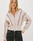 Woman wearing a beige zip-up sweater with details on a white background