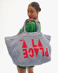 Woman holding a striped tote bag with red text on a white background
