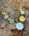 Gold necklace with various charms on a textured stone surface