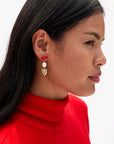 Woman wearing a red sweater and earrings with a white background