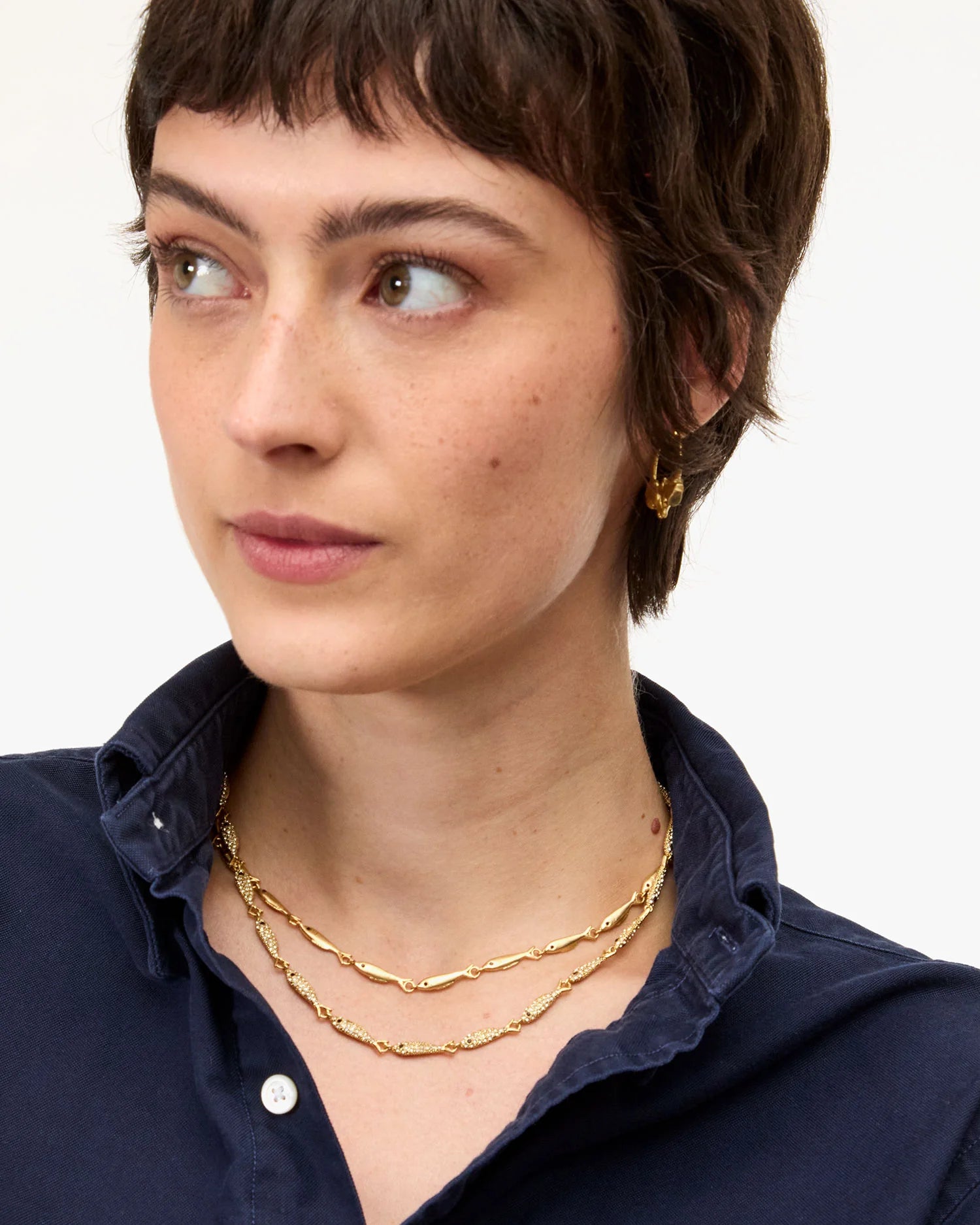 Woman wearing gold necklaces and earrings on a white background
