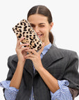 model holding a leopard clutch while wearing a stripe blazer over a stripe shirt on a white background
