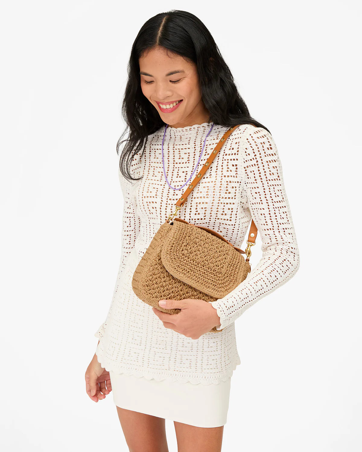 Woman holding a woven handbag against a white background