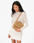 Woman holding a woven handbag against a white background