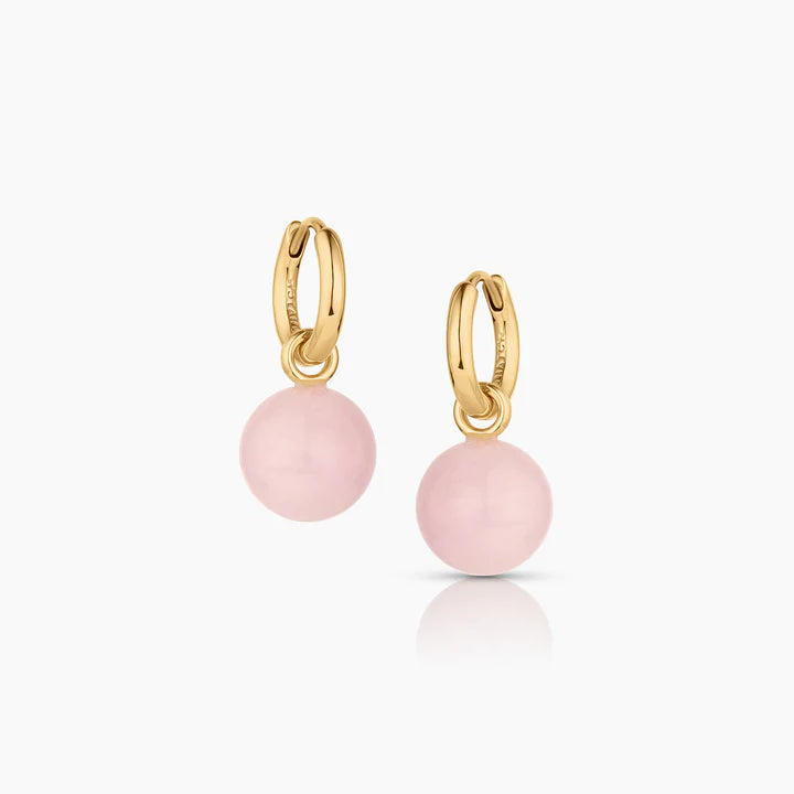 Gold hoop earrings with pink spherical charms on a white background