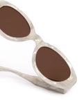 Sunglasses with brown lenses and a white frame on a white background