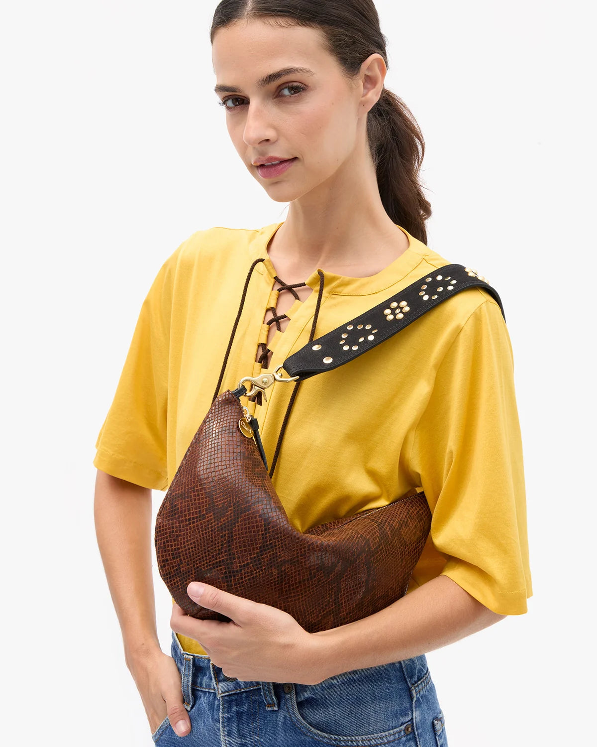 a model in a yellow shirt wearing the python lune bag on a white background