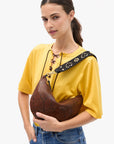 a model in a yellow shirt wearing the python lune bag on a white background