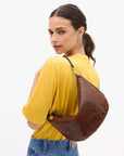 a model in a yellow shirt wearing the python lune bag on a white background