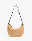 Beige handbag with black strap on a white background