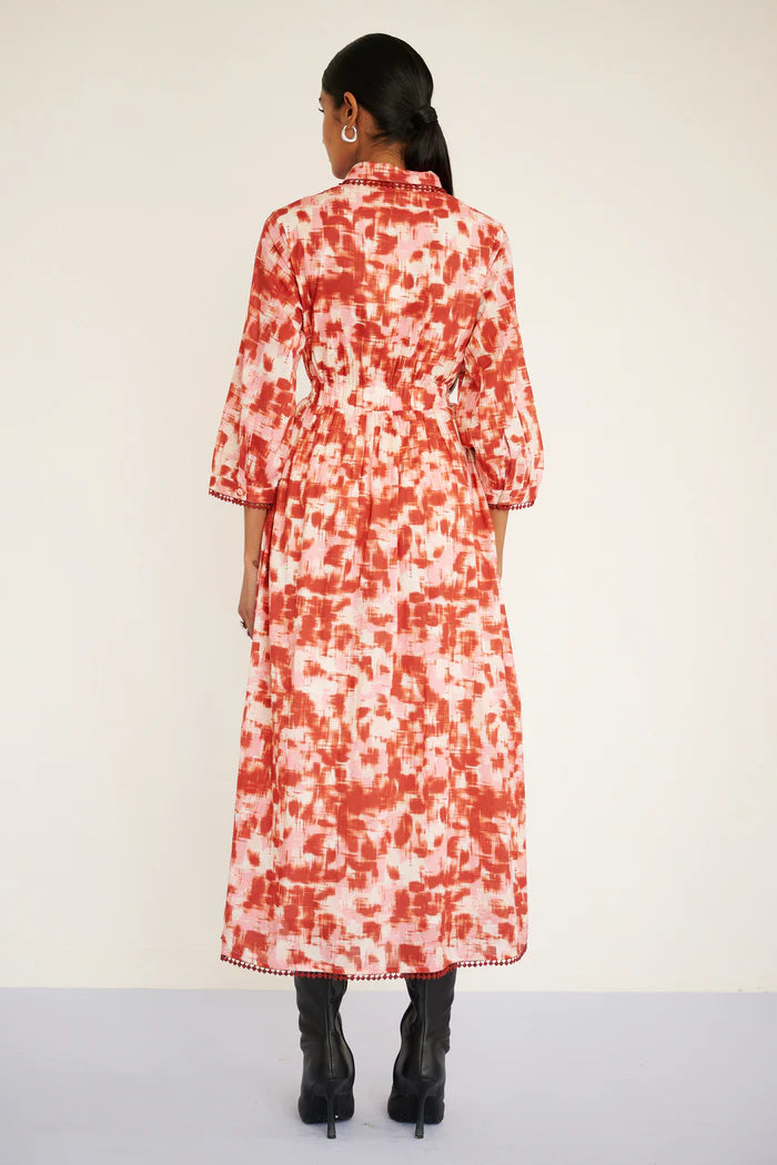 Person wearing a red and white floral dress on a plain background, back