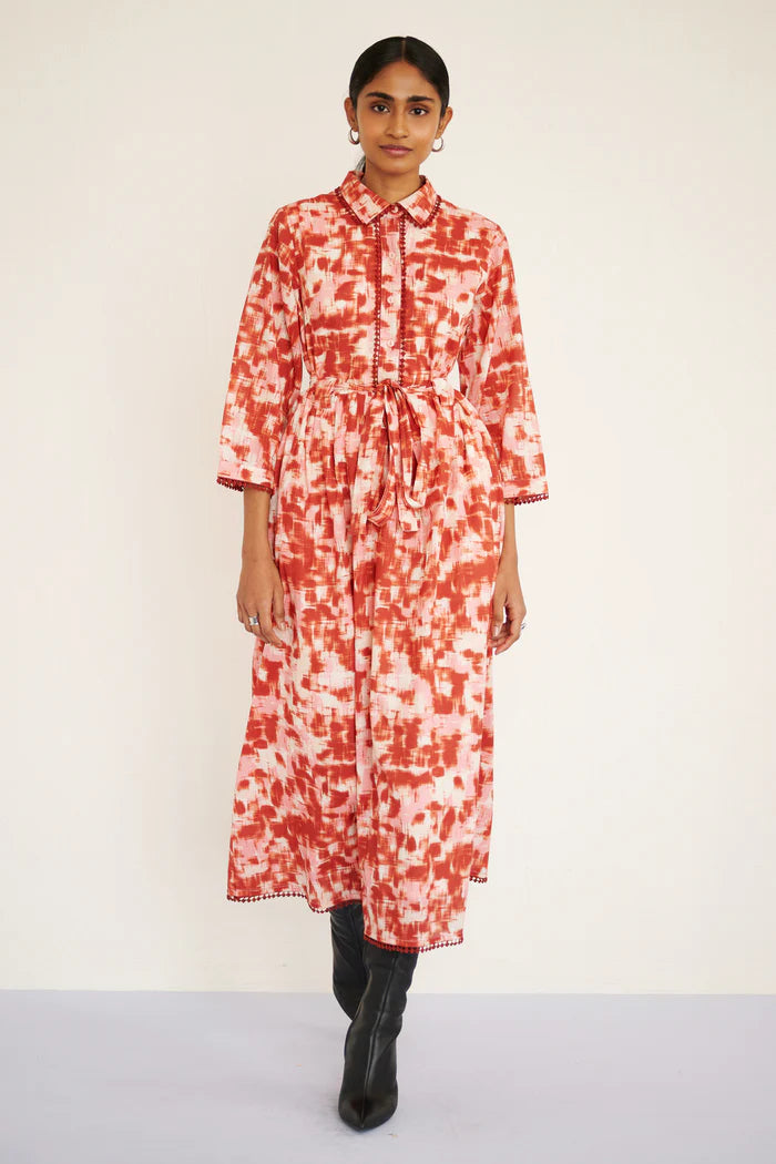 Woman wearing a red and white patterned dress on a white background, front