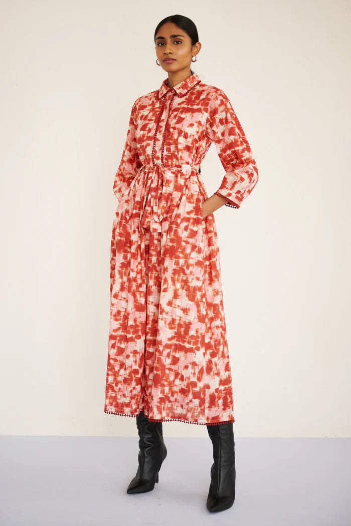 Woman wearing a red and white patterned dress with black boots on a plain background