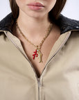 Close-up of a person wearing a gold necklace with a red pendant and a fish symbol.