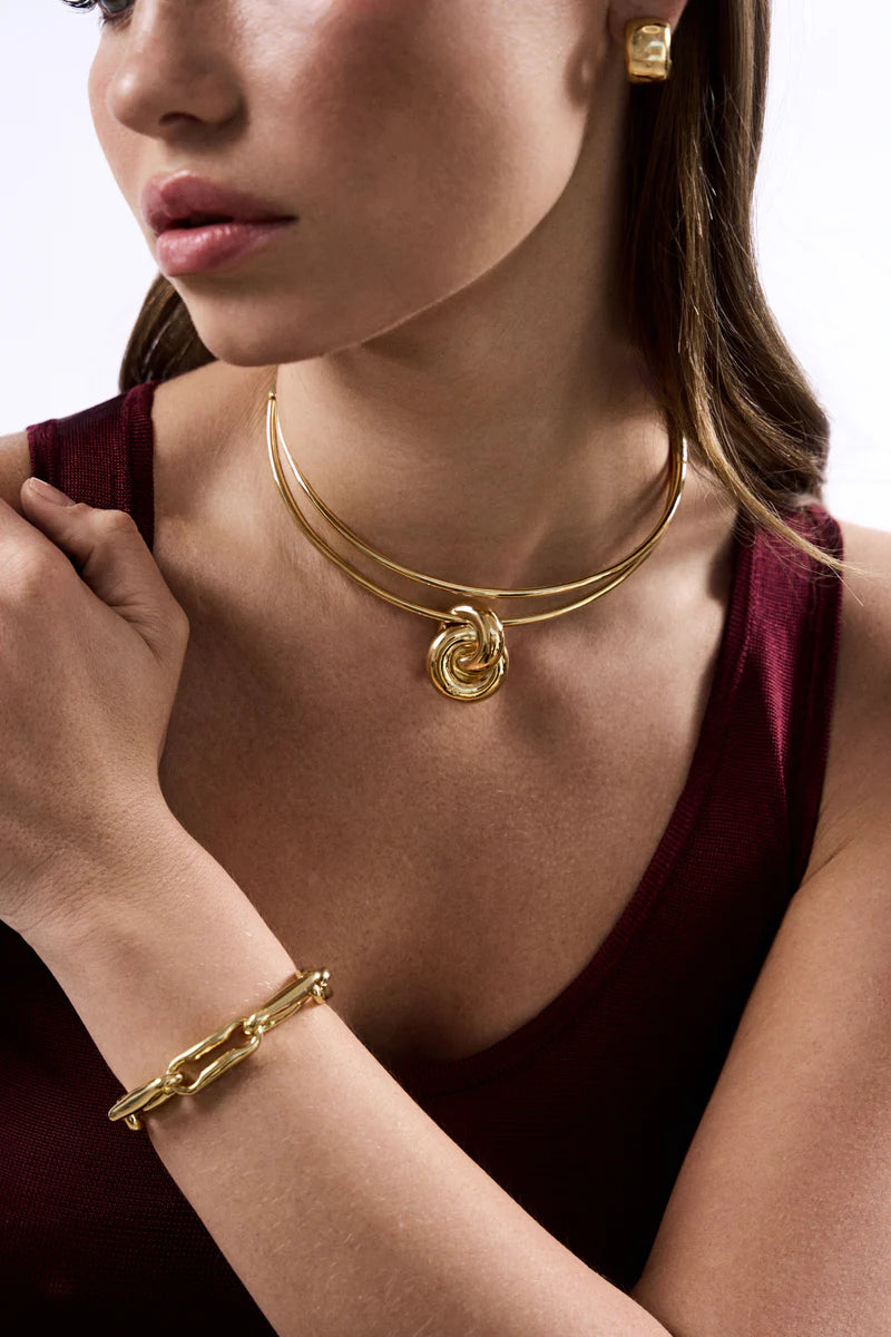Woman wearing gold jewelry including a necklace, bracelet, and earrings.
