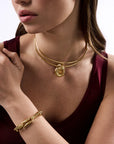 Woman wearing gold jewelry including a necklace, bracelet, and earrings.