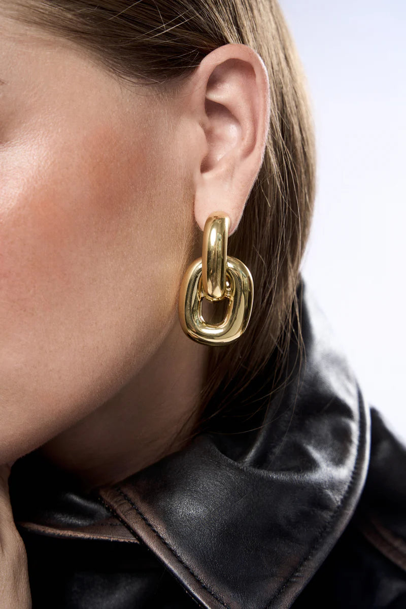 Gold hoop earring worn by a person with a blurred background