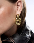 Gold hoop earring worn by a person with a blurred background