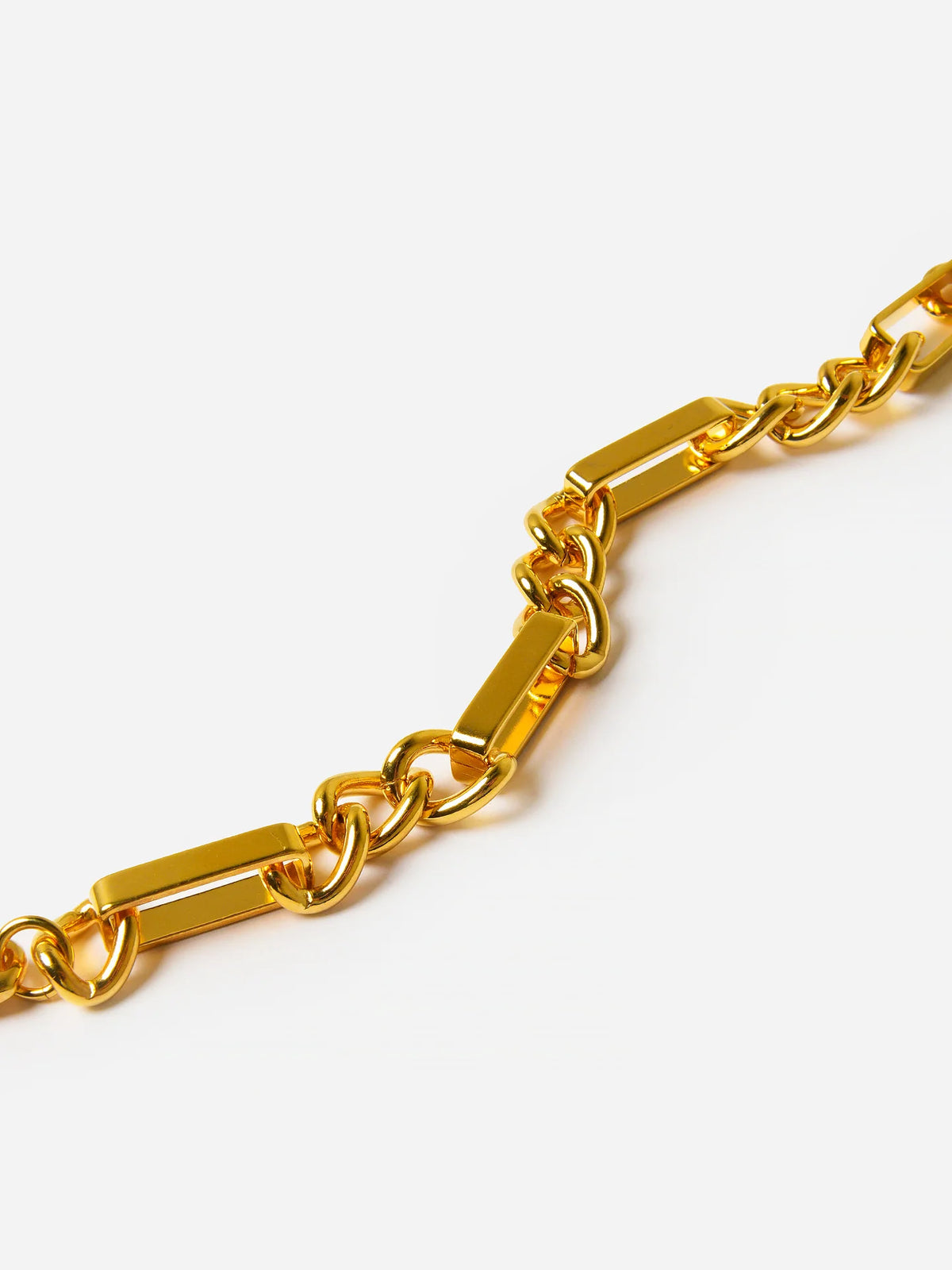 A close-up of a polished gold-tone chain link bracelet featuring rectangular bar links alternating with smaller oval links, set against a clean white background.