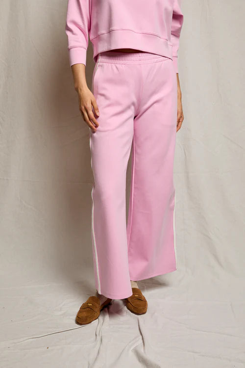 Person wearing a pink outfit with wide-leg pants on a plain background