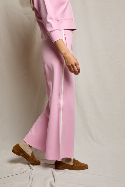 Person wearing a pink outfit with wide-leg pants on a plain background
