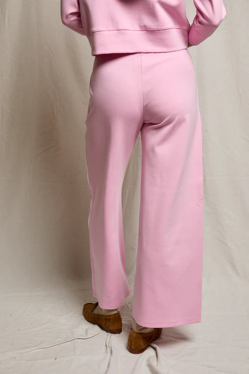 Person wearing a pink outfit with wide-leg pants on a plain background