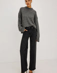 model wearing a grey sweater with black jeans on a grey background