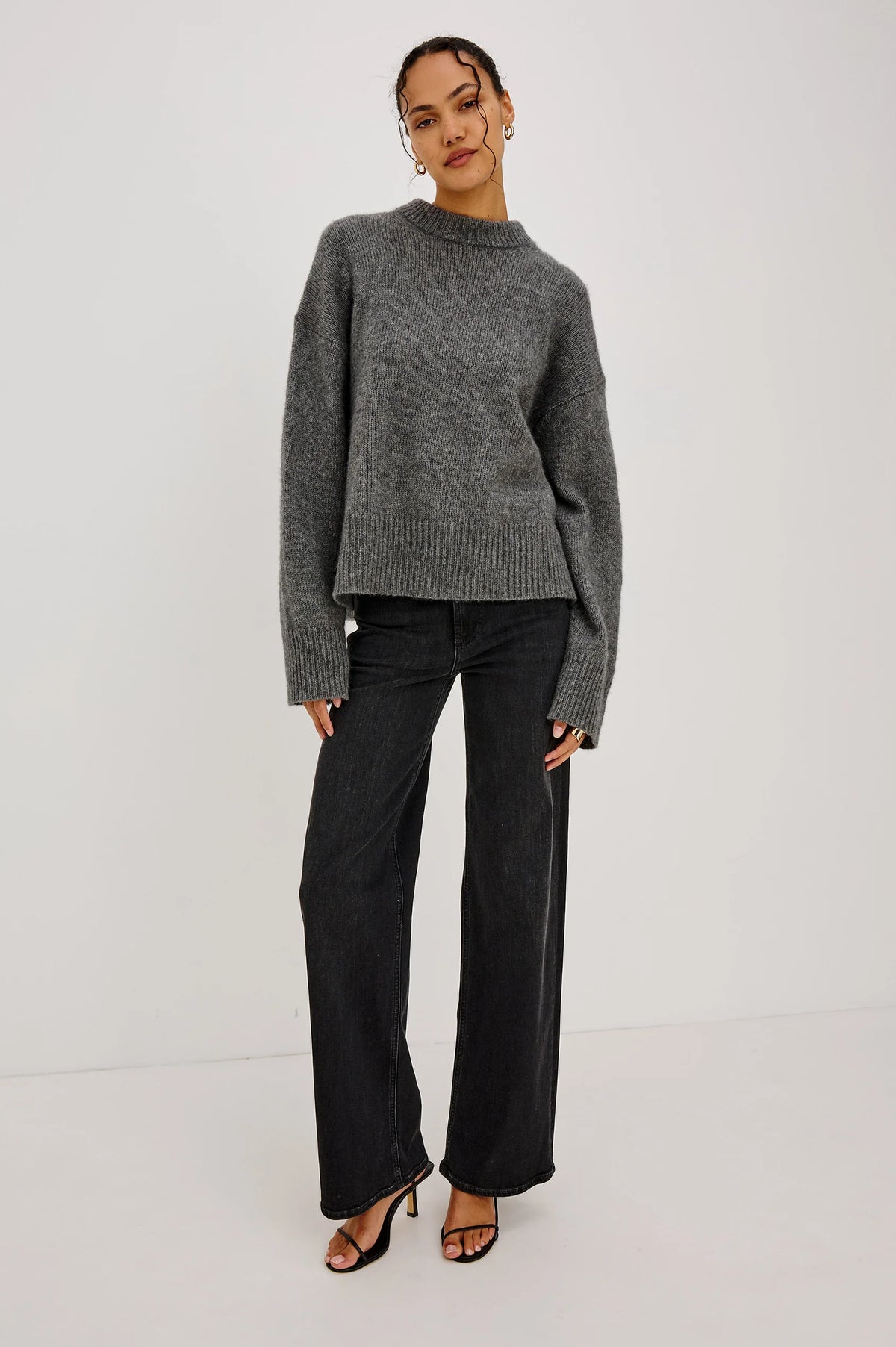 model wearing a grey sweater with black jeans on a grey background