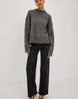 model wearing a grey sweater with black jeans on a grey background