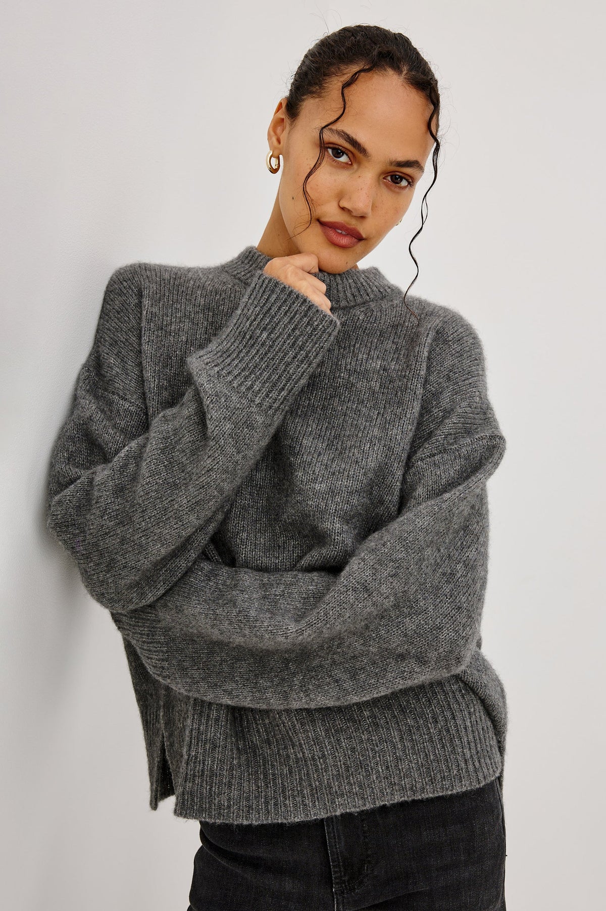 model wearing a grey sweater with black jeans on a grey background
