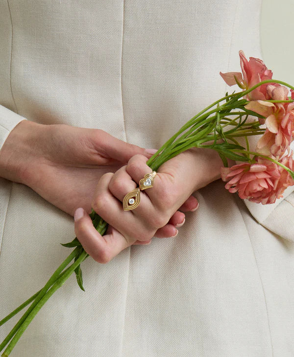  groovy diamond heart signet ring on pinky finger on a model holding flowers