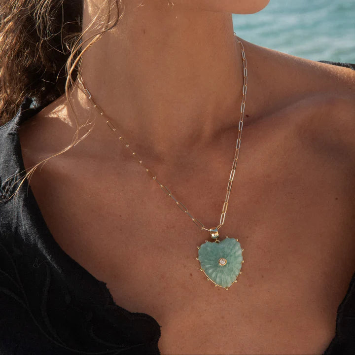 Necklace with a heart-shaped pendant worn by a person by the water