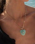 Necklace with a heart-shaped pendant worn by a person by the water