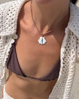 Person wearing a white crochet cover-up and purple bikini on a beach.