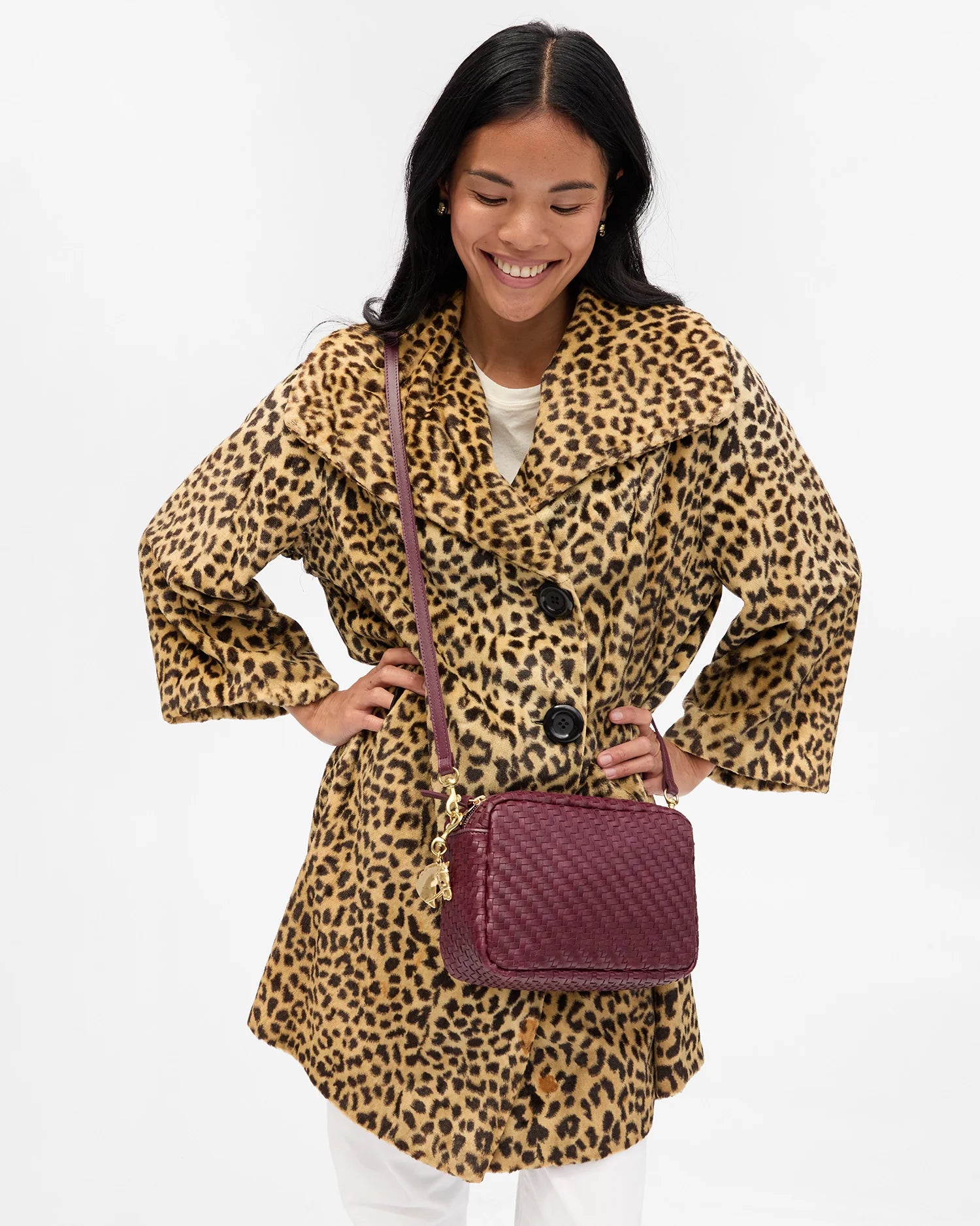 Woman wearing a leopard print coat with a purple handbag on a white background