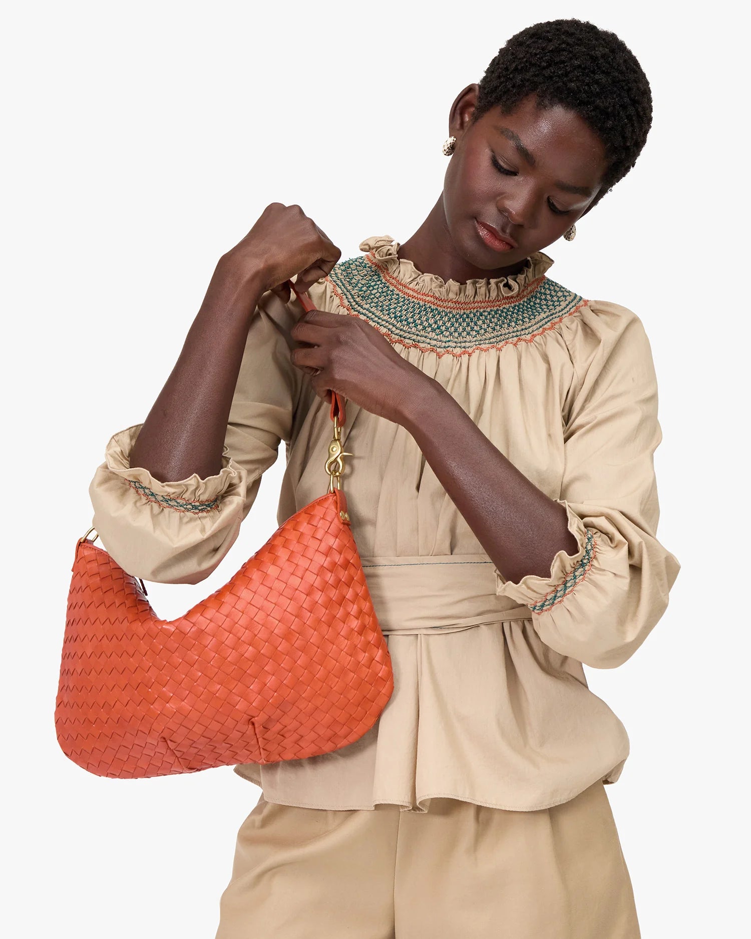 Woman holding a Moyen Messenger Saltillo Diagonal Woven against a white background
