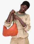 Woman holding a Moyen Messenger Saltillo Diagonal Woven against a white background