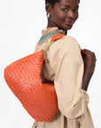 Woman carrying an orange woven handbag on shoulder
