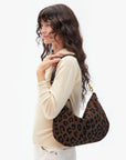 Woman holding a leopard print handbag against a white background