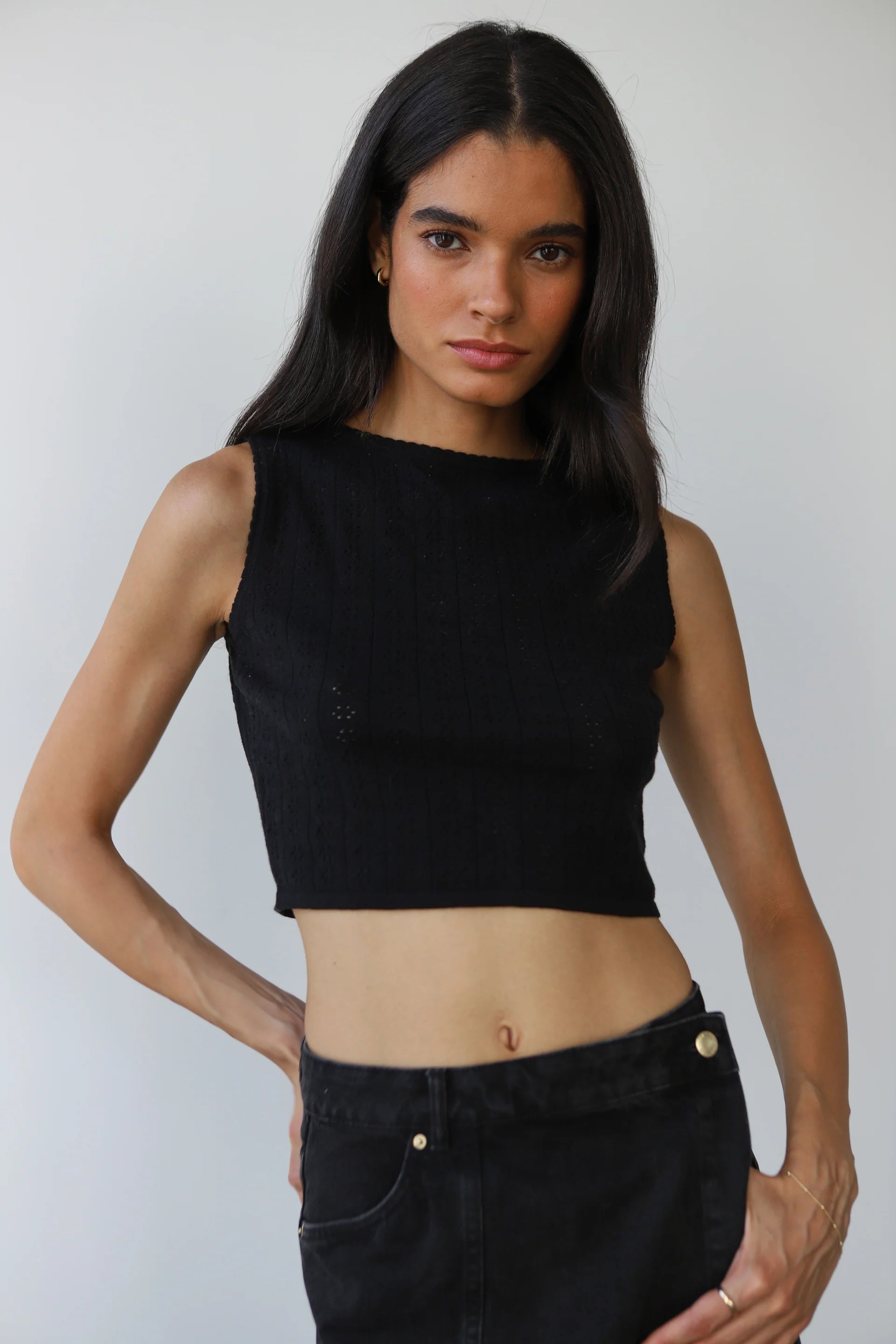 Woman wearing a black sleeveless top and black pants against a plain background