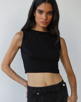 Woman wearing a black sleeveless top and black pants against a plain background